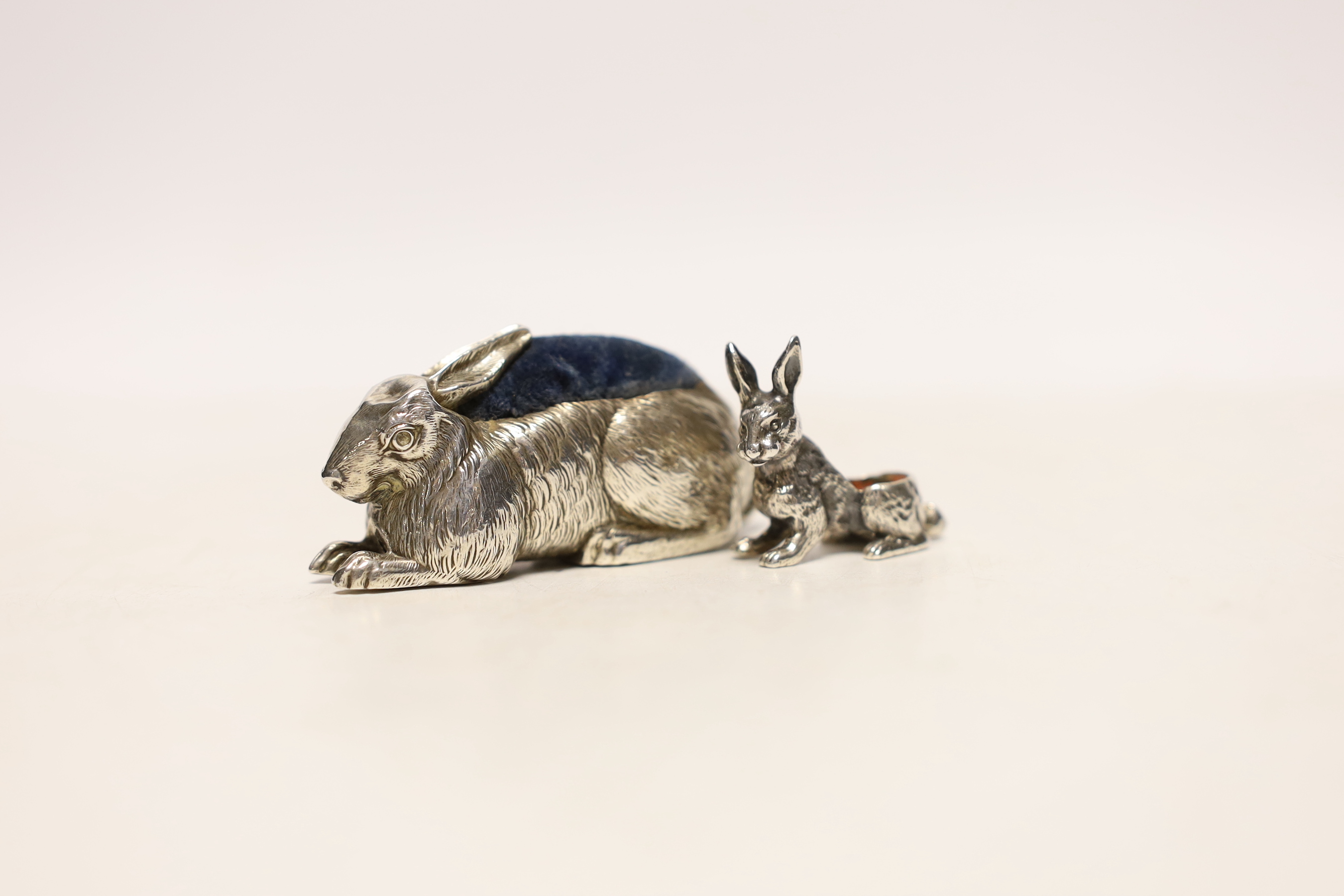 An Edwardian novelty silver pin cushion, modelled as a hare, ?M, Birmingham, 1907, length 67mm and a small white metal model hare pin cushion, lacking cushion.